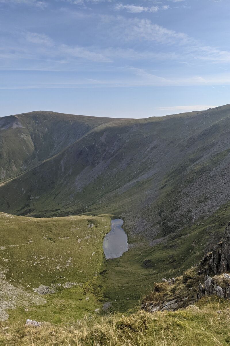 A valley with a small lake in it from the top of Yr Elen